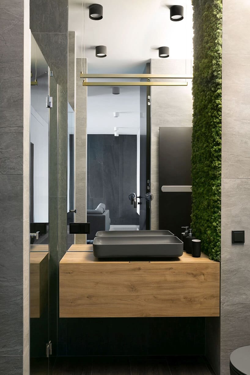 łazienka z umywalką w formie dużej mydelnicy w szarym odcieniu przy ścianie z zielonym mchem
