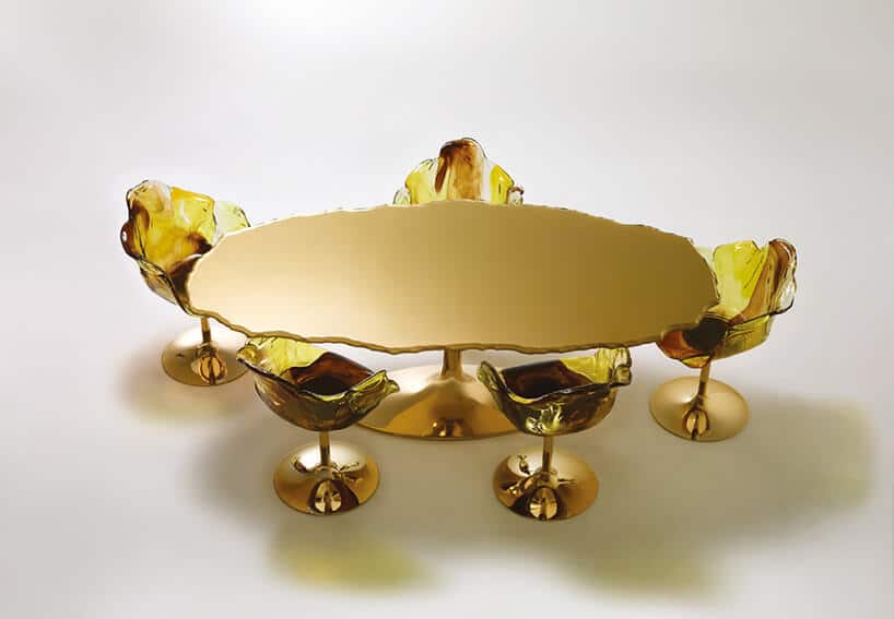 owalny złoty stolik z nieregularnym blatem i pięcioma złotymi krzesłami